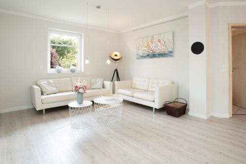 a white living room with two couches and a table at Haus Sommerzeit in Fissau
