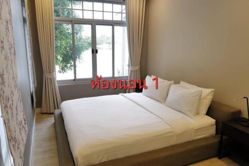 a bedroom with a large white bed with a window at Mazecape in Ban Hua Khwai