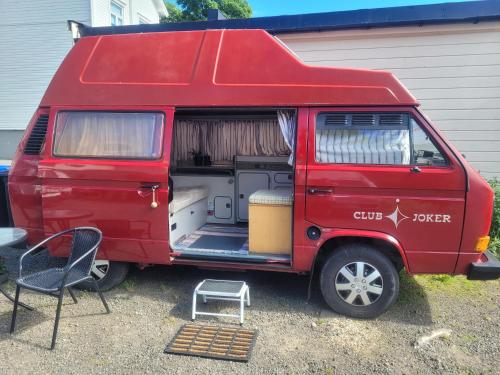 a red van with its door open sitting outside a garage at Sleep inside a classic Volkswagen Westfalia or our legendary Mercedes Düdo overland cabin in central Svolvær Close to public showers and toilets NO PARKING in Svolvær