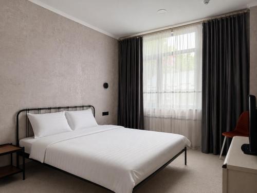 a bedroom with a white bed and a window at AiTumar boutique hotel in Almaty