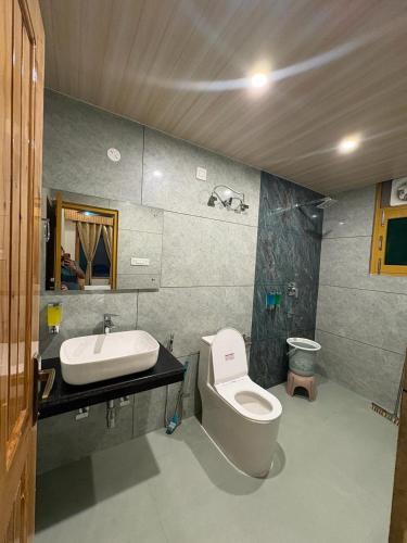 a bathroom with a toilet and a sink at Tulip Flowing River View Hotel. in Shamshi