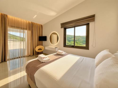a bedroom with a large white bed with a window at Meliora Exclusive Villas Parga in Parga