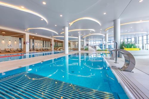 a large swimming pool with blue water in a building at Happy Land Aqua Polanki B405 in Kołobrzeg
