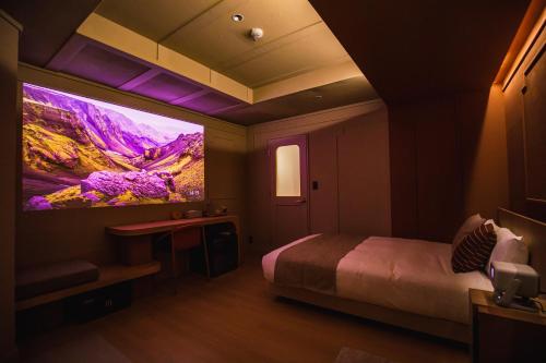 a room with a bed and a large tv on the wall at SABLIER by R HOTEL in Osaka