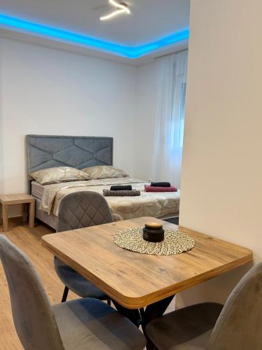 a room with a table and chairs and a bed at Taca 2 - Airport apartman in Surčin