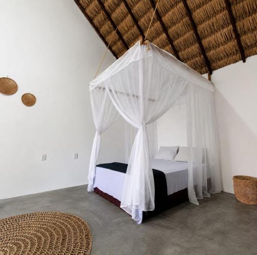 a bedroom with a bed with a mosquito net at ArpoadorBangalôparaísoperdido in Tutóia