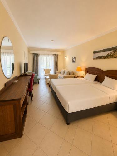 ein Hotelzimmer mit einem großen Bett und einem Schreibtisch in der Unterkunft Okaliptus Otel in Bitez