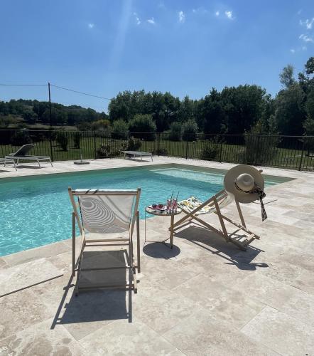 a pair of chairs and a hat next to a pool at Auberge Gardoise in Vallérargues