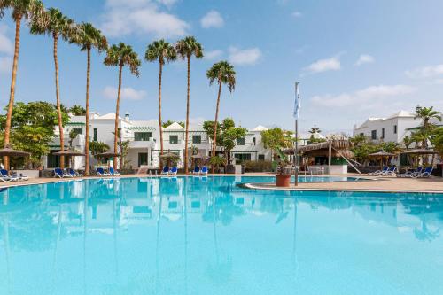 a large swimming pool with palm trees in the background at THB Royal in Playa Blanca