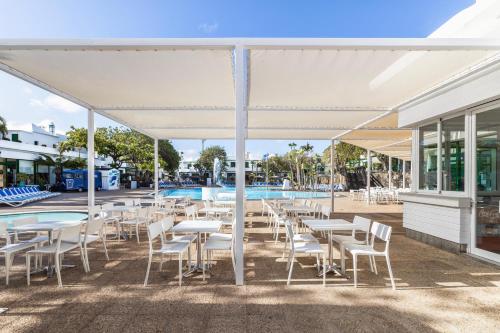 a patio with tables and chairs and a pool at THB Royal in Playa Blanca