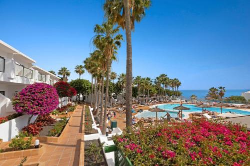 ein Resort mit Swimmingpool, Palmen und Blumen in der Unterkunft Hotel THB Flora in Puerto del Carmen