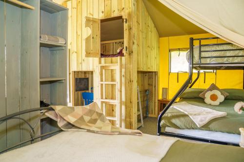 a bedroom with a bunk bed and a yellow wall at The Firs Glamping in Welland