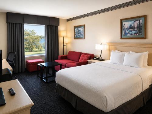 a hotel room with a bed and a red chair at Ramada by Wyndham Trenton in Trenton