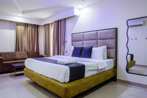 ein Schlafzimmer mit einem großen Bett und einer Couch in der Unterkunft Romeneo Grand Royal Hotel in Lagos