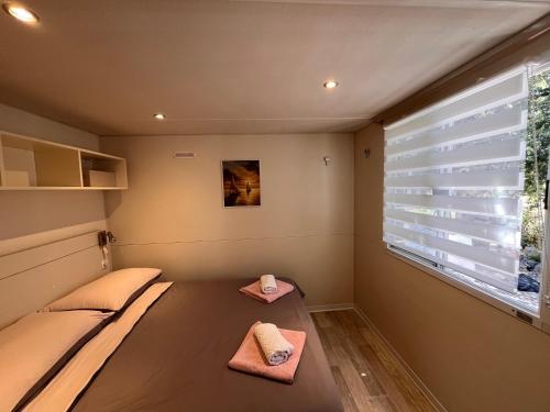 a room with two beds and a window with blinds at Mobile Home Ana Mia in Biograd na Moru