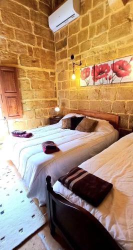 a bedroom with two beds and a brick wall at Mithna farmhouse in Għarb