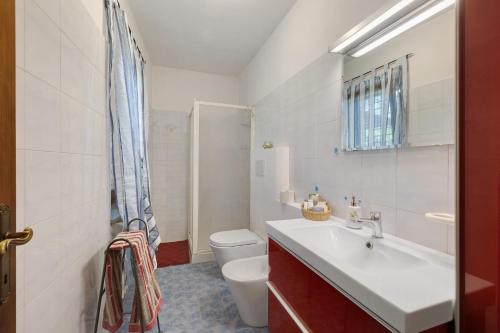 a white bathroom with a sink and a toilet at Casa Centomila Volte Benvenuti in Tigliole