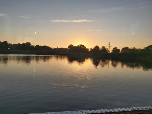 a view of a lake with the sunset in the background at Hausboot MeerZeit in Wangerland