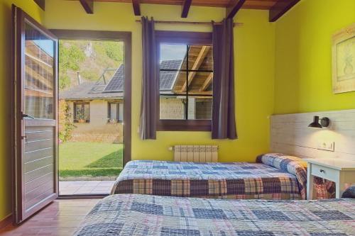 two beds in a room with yellow walls and a window at Ribera del Cantero in Ponferrada