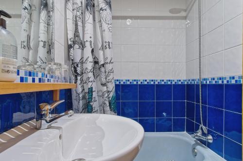 a bathroom with a sink and a blue and white shower curtain at Ribera del Cantero in Ponferrada