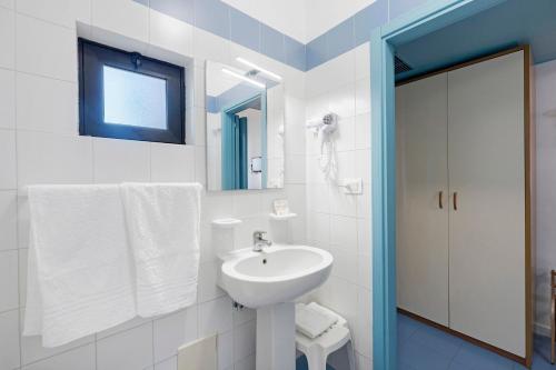a white bathroom with a sink and a mirror at Marina Living Rooms and Pool in Paestum