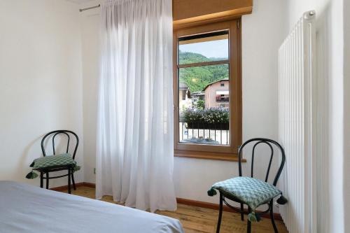 a bedroom with two chairs and a window at Alla Loggia dell'Imperatore in Levico Terme