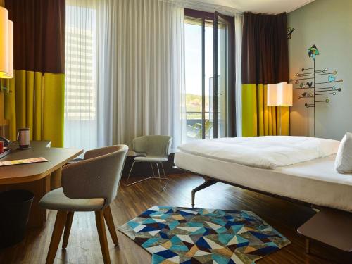 a bedroom with a bed and a desk and chairs at 25hours Hotel Zürich West in Zurich