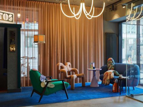 a living room with chairs and tables and a chandelier at 25hours Hotel beim MuseumsQuartier in Vienna