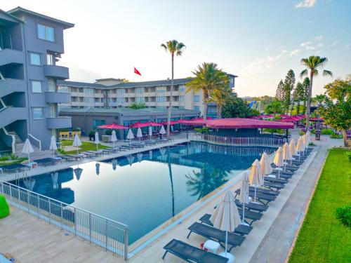 a large swimming pool with chairs and umbrellas next to a hotel at Senza Sunset Beach Hotel in Alanya