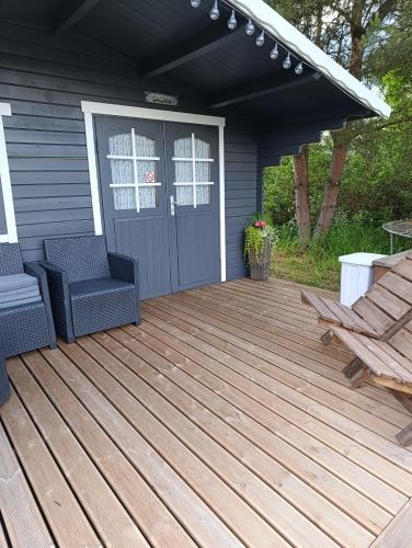 a wooden deck with two chairs and a door at Kolkja Holiday Centre -Kolkja Puhkeküla in Kolkja