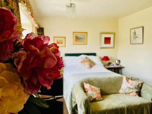 a bedroom with a bed and a chair and flowers at Garwood House in Holt