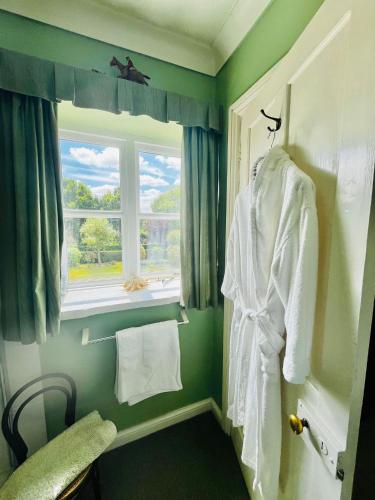 a bathroom with a window and a white robe at Garwood House in Holt