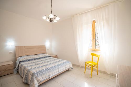 a bedroom with a bed and a yellow chair at Villa Chiara Infinity Sea View in Mandaradoni
