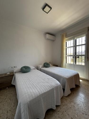 two beds in a white room with a window at Brisa de Pinares in Barbate