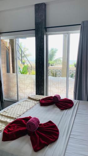 a bed with two red bows on top of it at Le Petit Hotel & Restaurant in Negombo