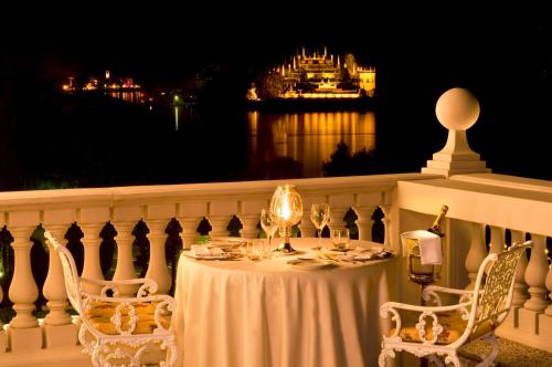 a table and chairs on a balcony at night at Grand Hotel Bristol in Stresa