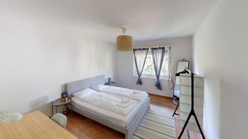a white room with a bed and a table at Charming 3 Bedroom Retreat in Zurich