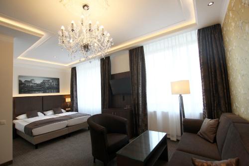 a hotel room with a bed and a chandelier at Hotel Europäischer Hof in Elsterwerda