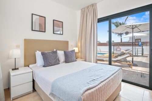 a bedroom with a bed and a balcony with a pool at Melia Villa II by Nomads in Kissonerga