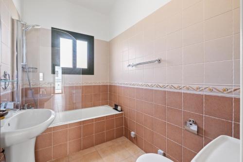 a bathroom with a tub and a sink and a toilet at Melia Villa II by Nomads in Kissonerga