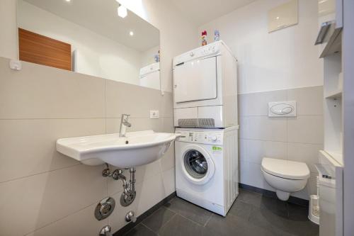 a bathroom with a sink and a washing machine at Apartments Villa Jim in Ortisei