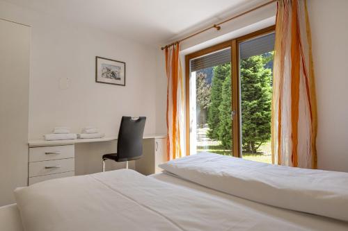 a bedroom with a bed and a desk and a window at Apartments Villa Jim in Ortisei