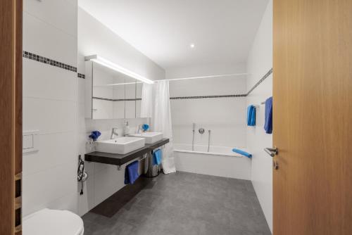 a white bathroom with a sink and a tub at Chasa Miramunt 2 in Scuol