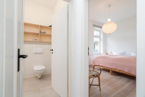 a bedroom with a pink bed and a bathroom at Ferienhaus Stranden Westfehmarn in Fehmarn