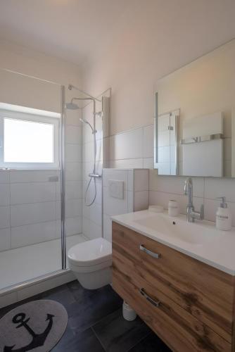 a bathroom with a sink and a toilet and a shower at Ankerplatz über dem Hafen - Pub in Pellworm