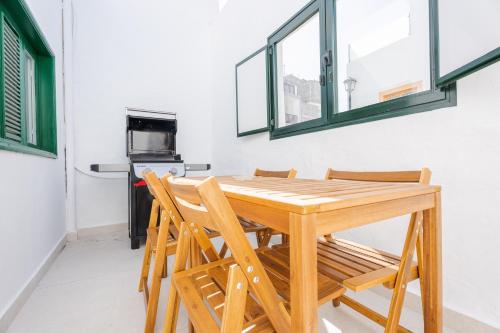 a wooden table and chairs in a kitchen with windows at Avocado Corner House - Charco de San Gines By Lanzarote Vacation Homes in Arrecife