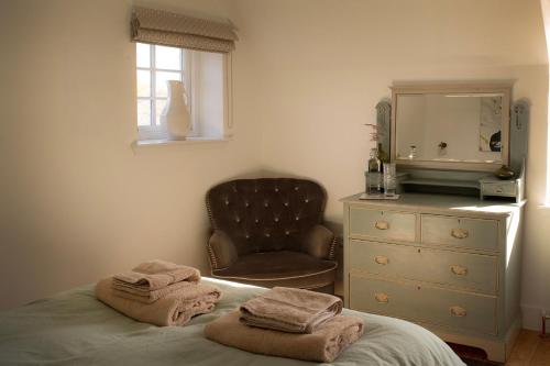 a bedroom with a bed and a chair and a mirror at Farmhouse with Loch Views in Gartocharn