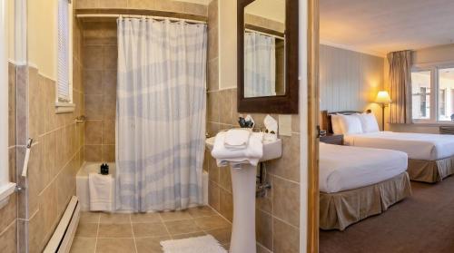 a bathroom with two beds and a sink and a shower at Gauthier's Saranac Lake Inn in Saranac Lake