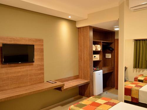 a hotel room with a tv and a bedroom at Hotel Matão By Mercure in Matão
