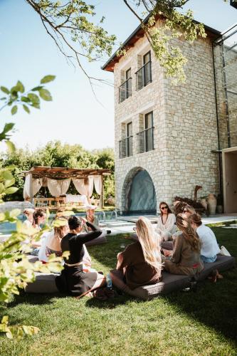 a group of people sitting on the grass in front of a building at Villa Si Era in Brataj